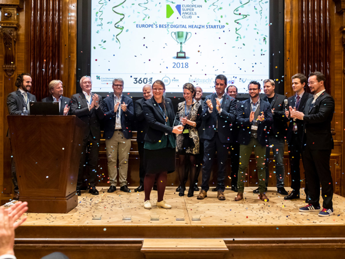 Fiona receiving the trophy for Digital Health Champion 2018, while sponsors, jury members and startup finalists are congratulating.